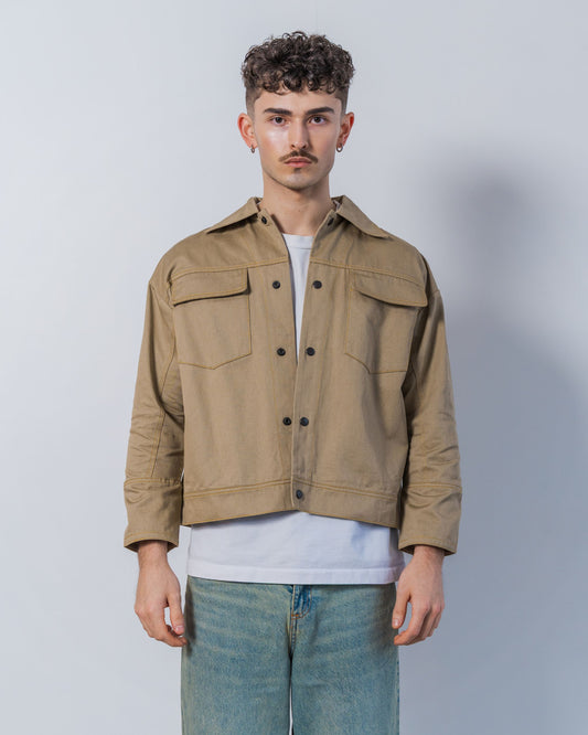 Man wearing a twill weave camel jacket over a white shirt with a plain background.