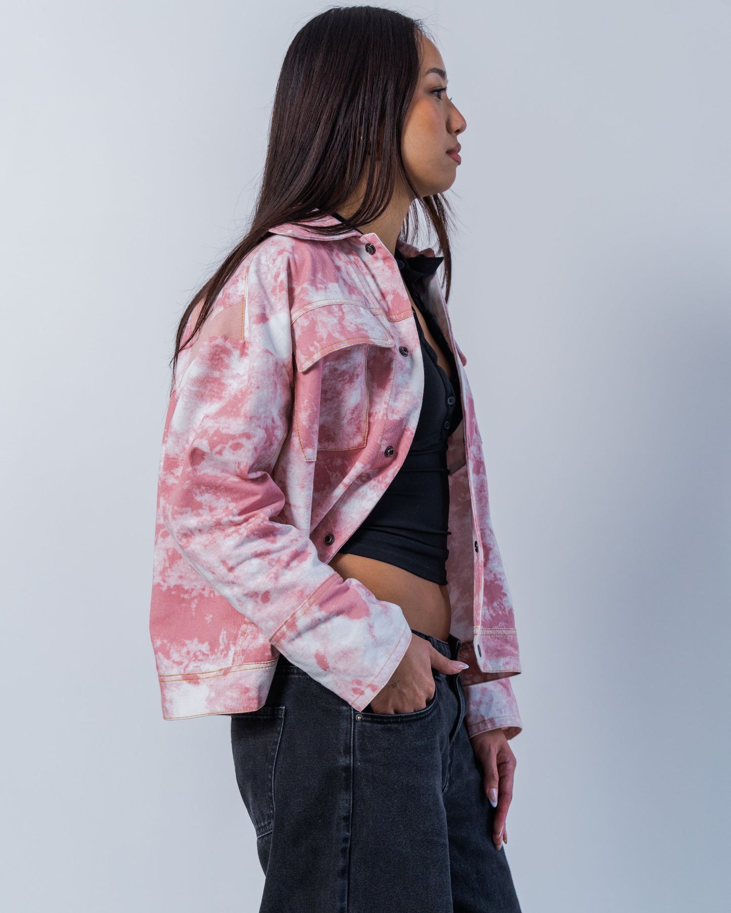 Person wearing a pink and white tie-dye jacket against a plain background