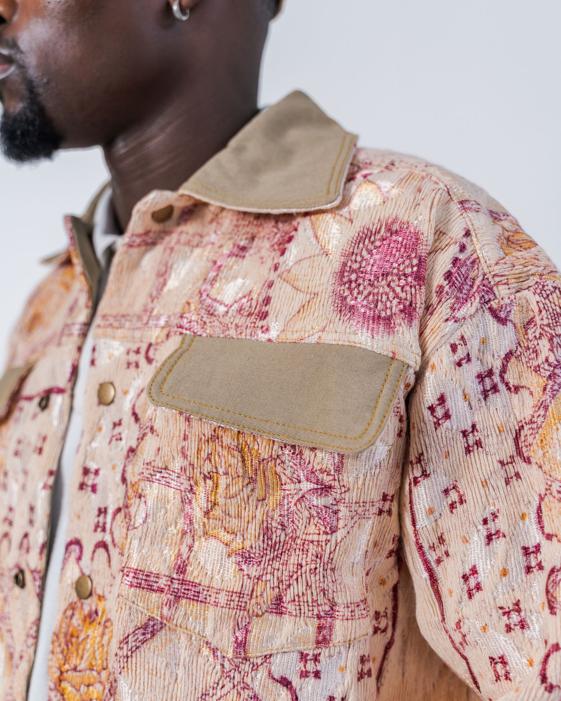Close-up on the pocket of a person wearing a patterned jacket made from sustainable upcycled fabric with a neutral background