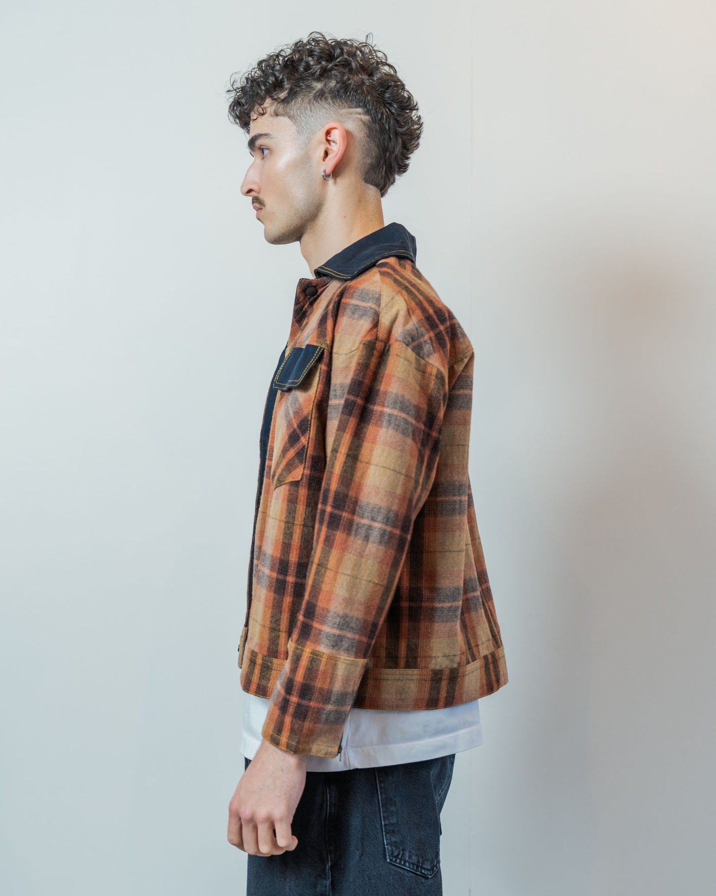 Man wearing a brown upcycled wool plaid jacket with a white background.