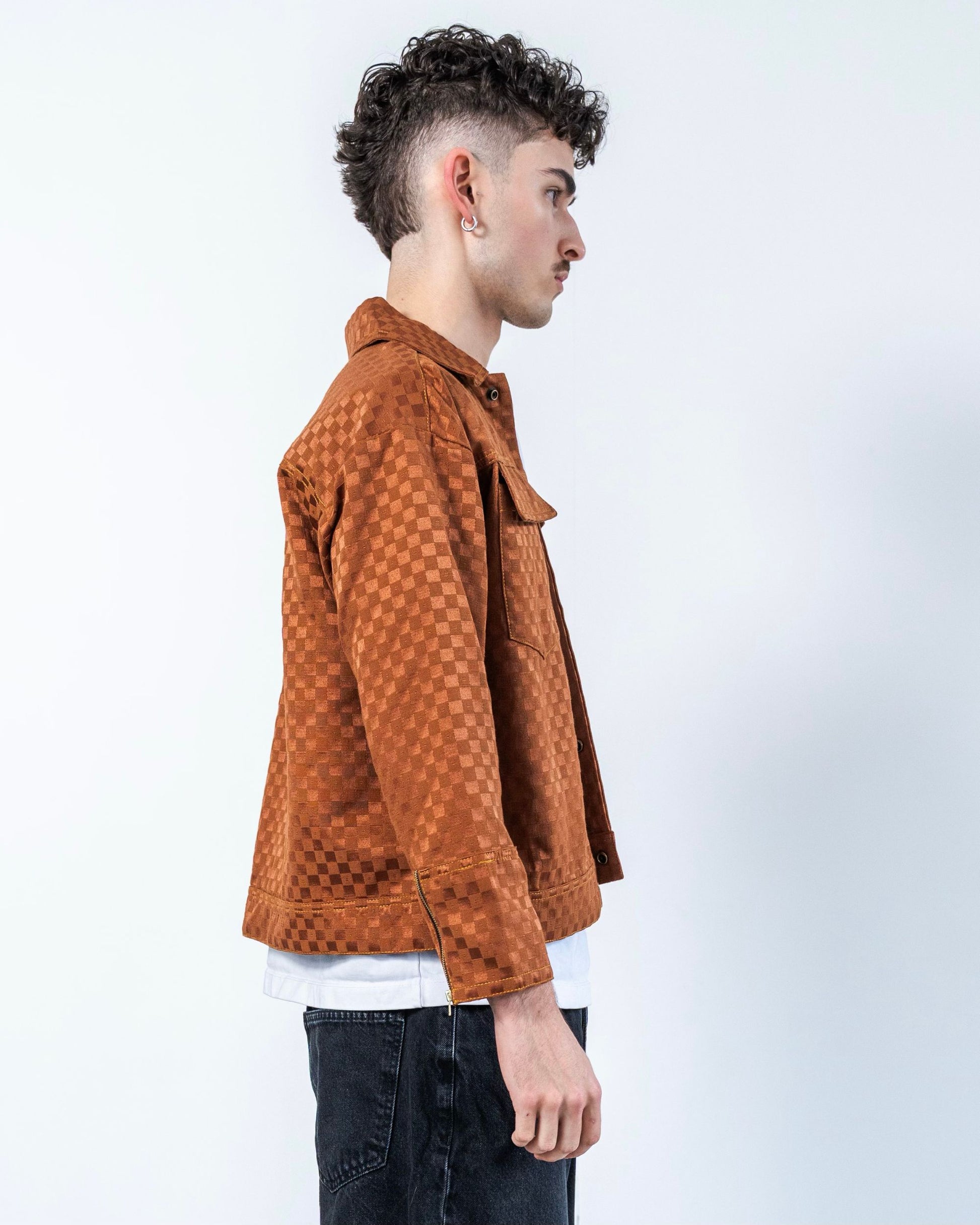 Person wearing a brown checkered textured jacket on a white background. The jacket is made from upcycled sustainable materials.