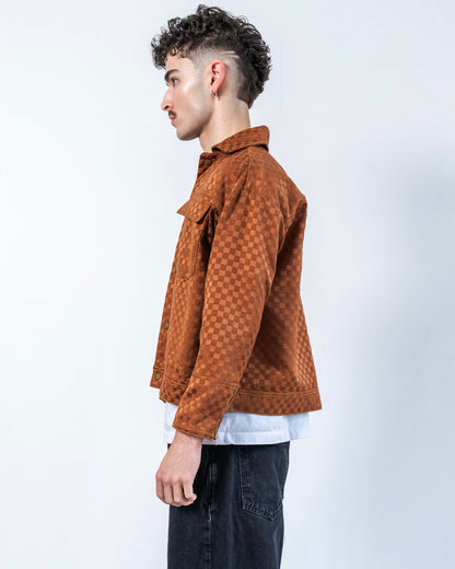 Person wearing a brown textured jacket with a checkers print on a white background
