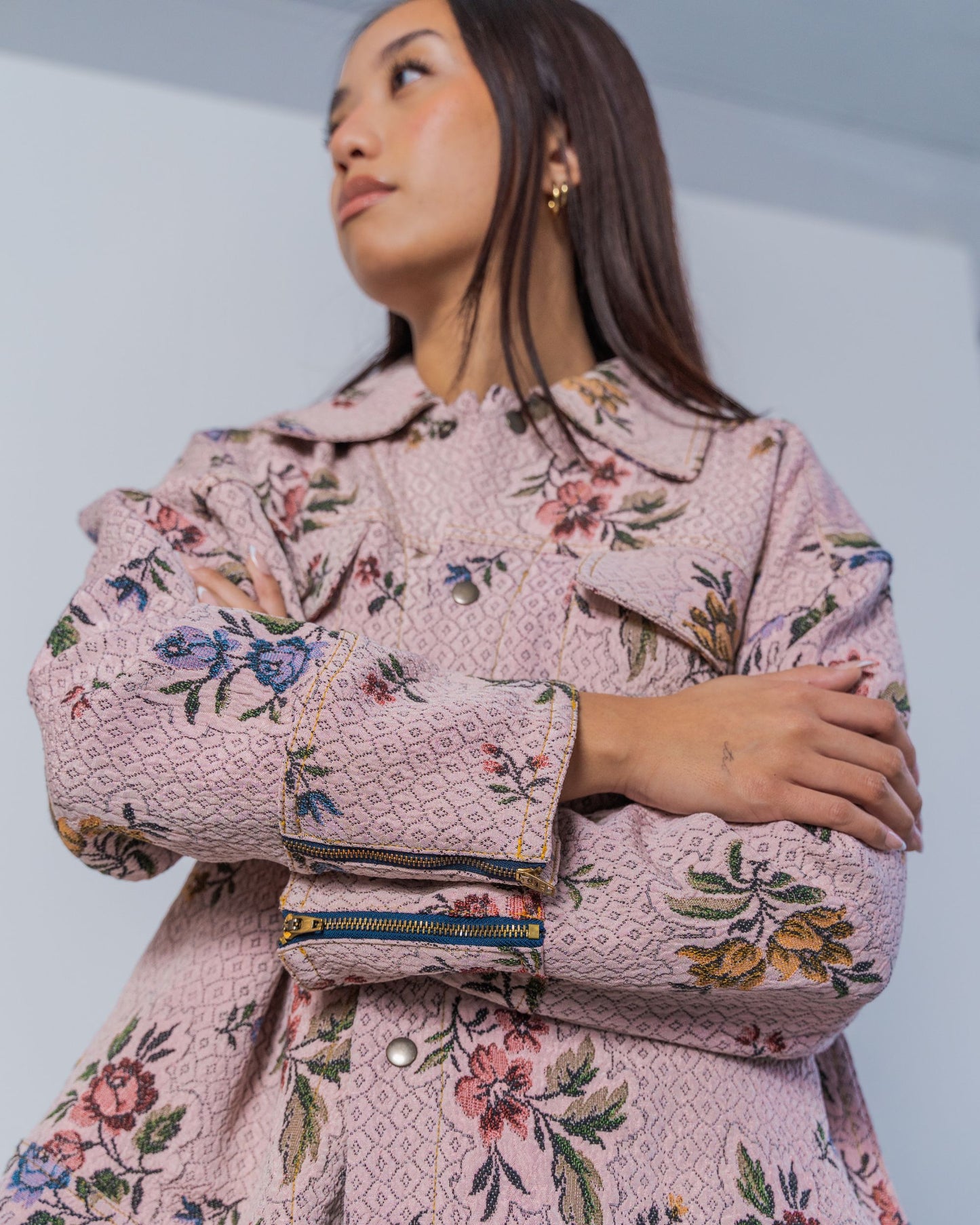 Woman wearing a pink floral patterned jacket against a plain background