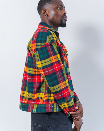 Man wearing a colorful upcycled wool plaid jacket against a plain background