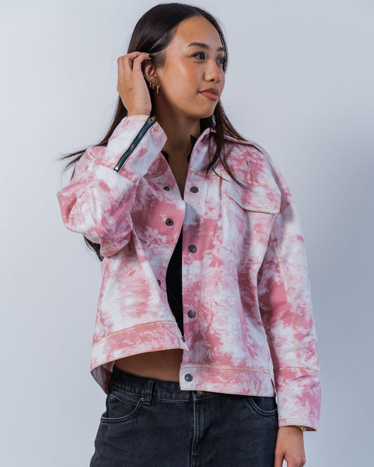 Person wearing a pink and white tie-dye jacket against a plain background. The jacket has snaps and gold top stitching