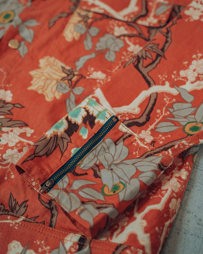Close up on the orange jacket with floral and bird printed upcycled brushed cotton. Showing the zipper detail on the cuff.