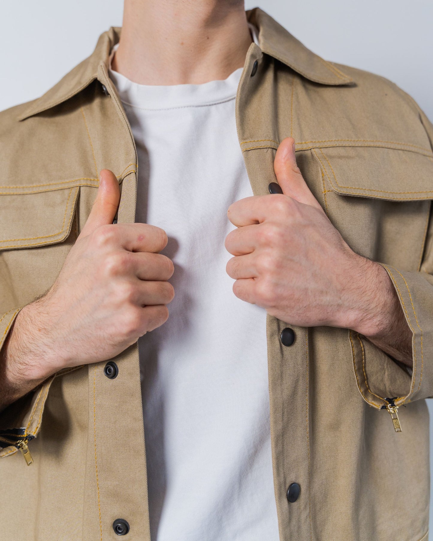Person wearing a twill weave camel jacket against a white background. The jacket is made from sustainable upcycled materials and unisex.