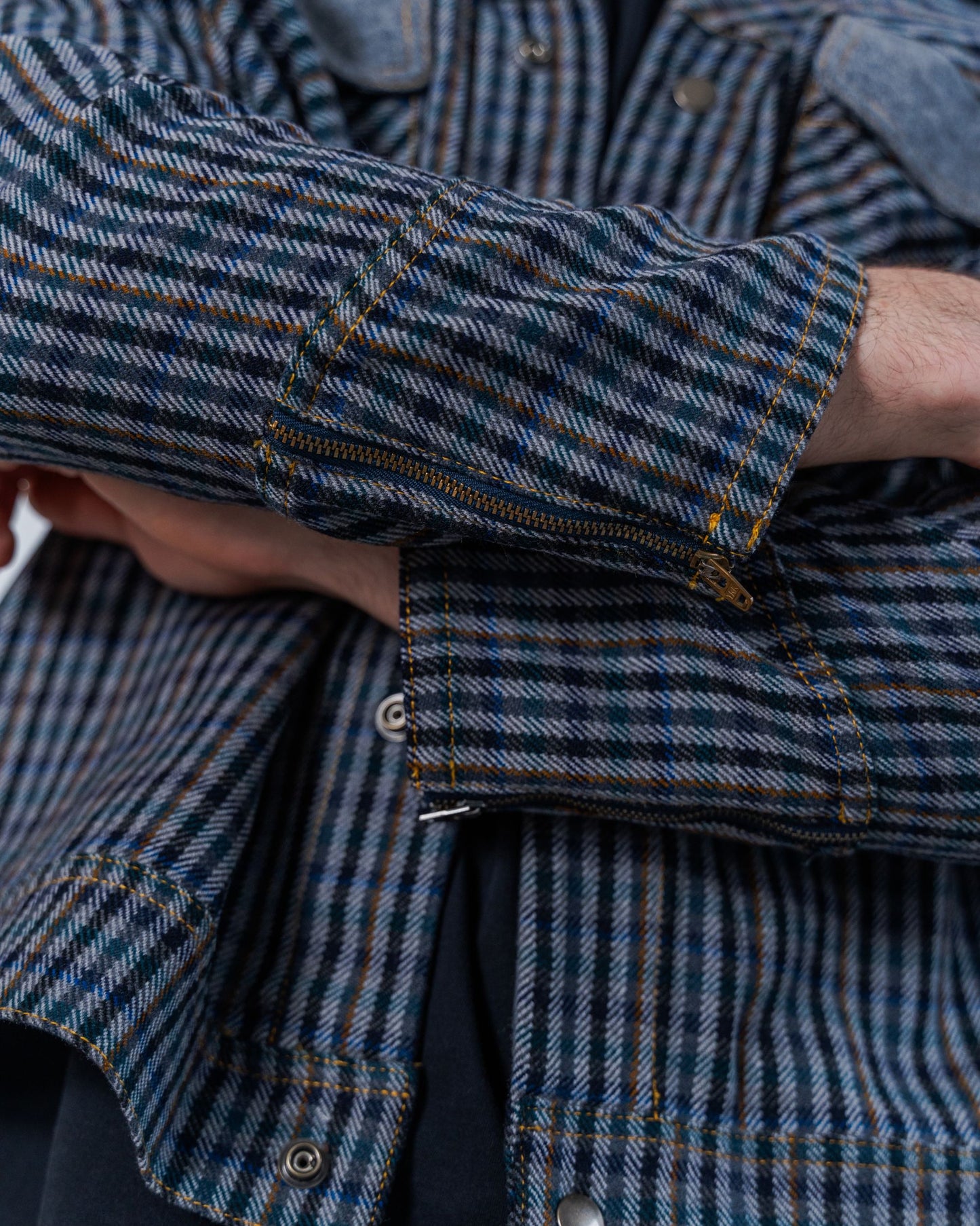 Close up details on the wool plaid fabric and zipper details on the cuff of the jacket. This photo also shows the snaps and the top stitching details. 