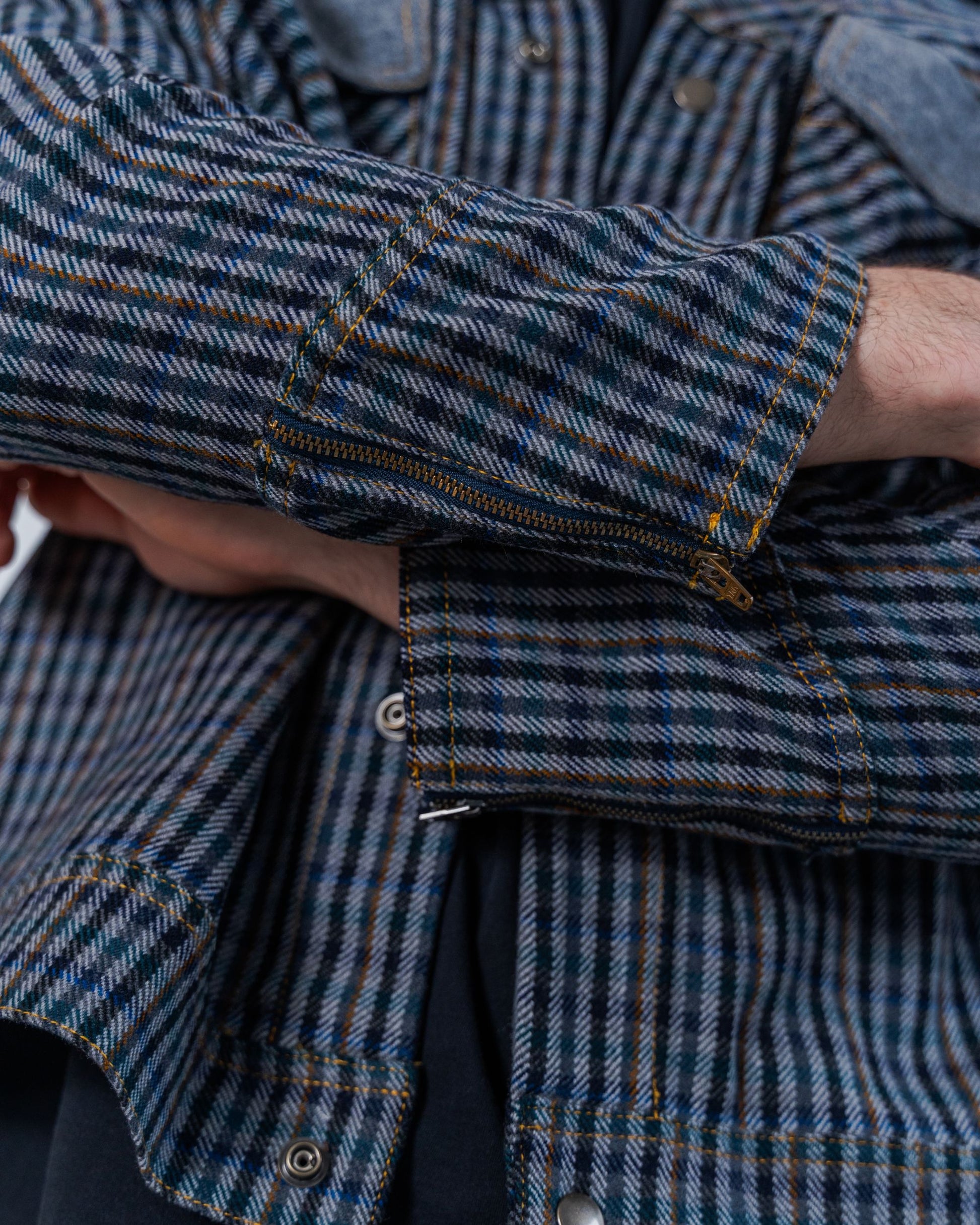 Close up details on the wool plaid fabric and zipper details on the cuff of the jacket. This photo also shows the snaps and the top stitching details. 