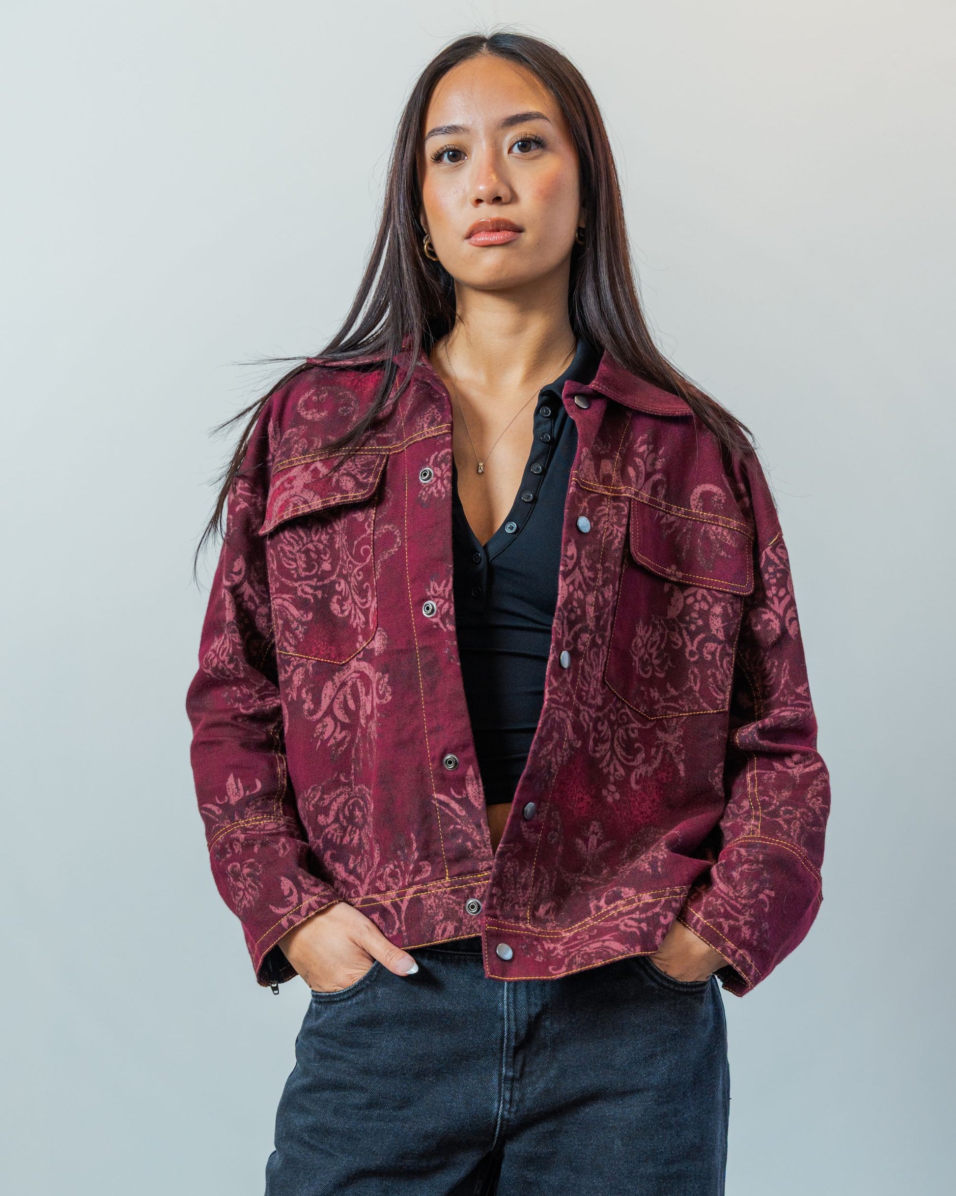 Woman wearing a patterned red sustainable upcycled jacket against a plain background