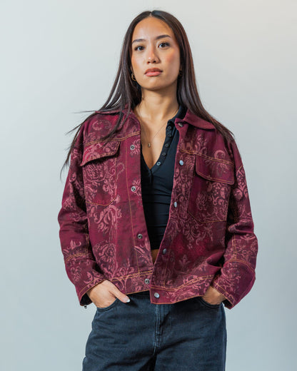 Woman wearing a patterned red sustainable upcycled jacket against a plain background