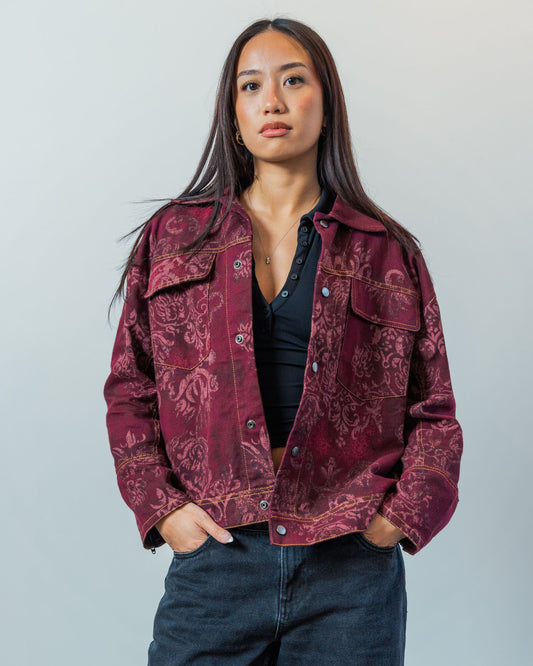 Woman wearing a patterned red sustainable upcycled jacket against a plain background