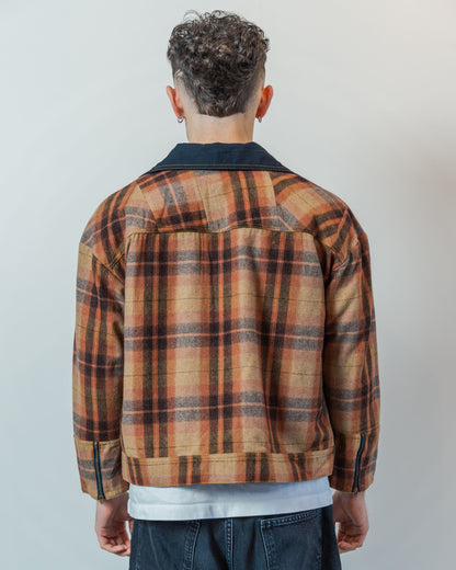Person wearing a brown plaid jacket with a neutral background. THe jacket is made from sustainable upcycled wool fabric.