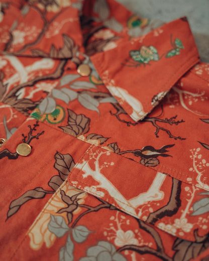 Close-up of a orange floral patterned jacket with gold snaps and gold top stitching