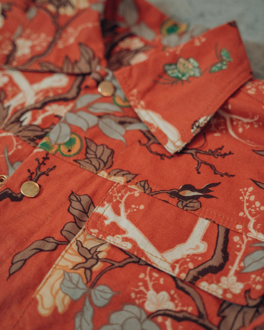 Close-up of a orange floral patterned jacket with gold snaps and gold top stitching