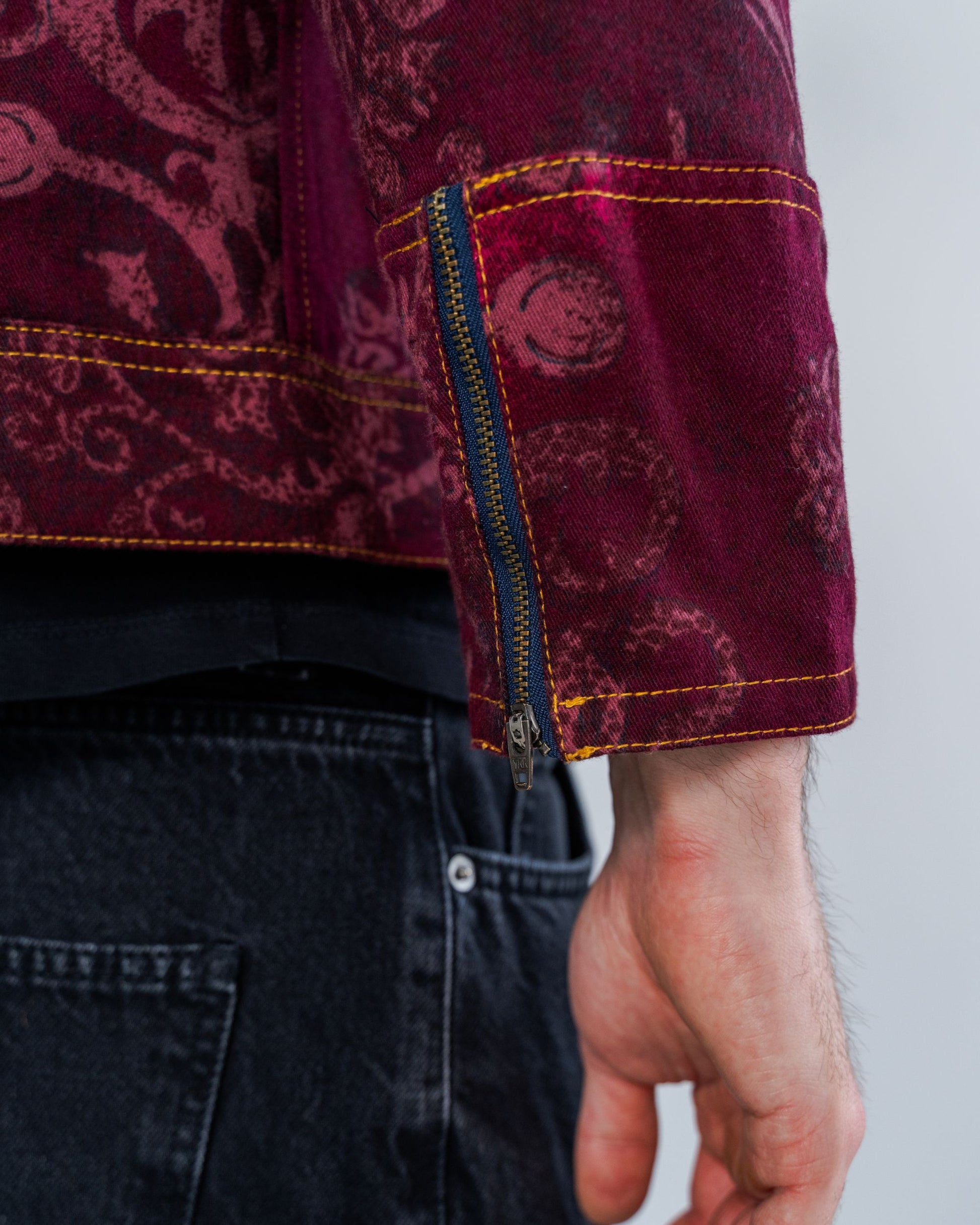 Close-up of a person wearing a burgundy patterned shirt with a zipper detail.