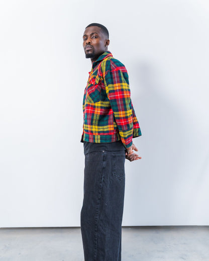 Person wearing a colorful upcycled wool plaid jacket and dark jeans against a white background