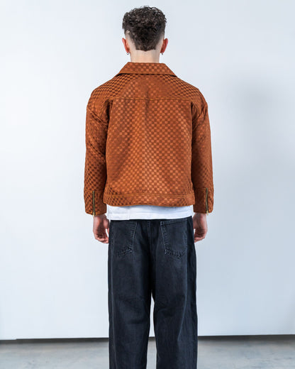 Person wearing a brown checkers patterned jacket and dark pants against a white background