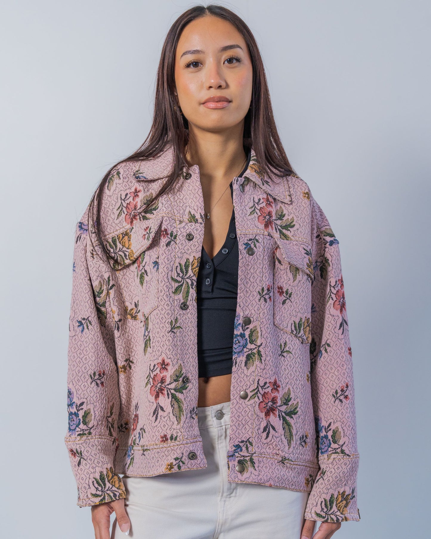 Woman wearing a unisex floral patterned jacket made from sustainable upcycled materials.