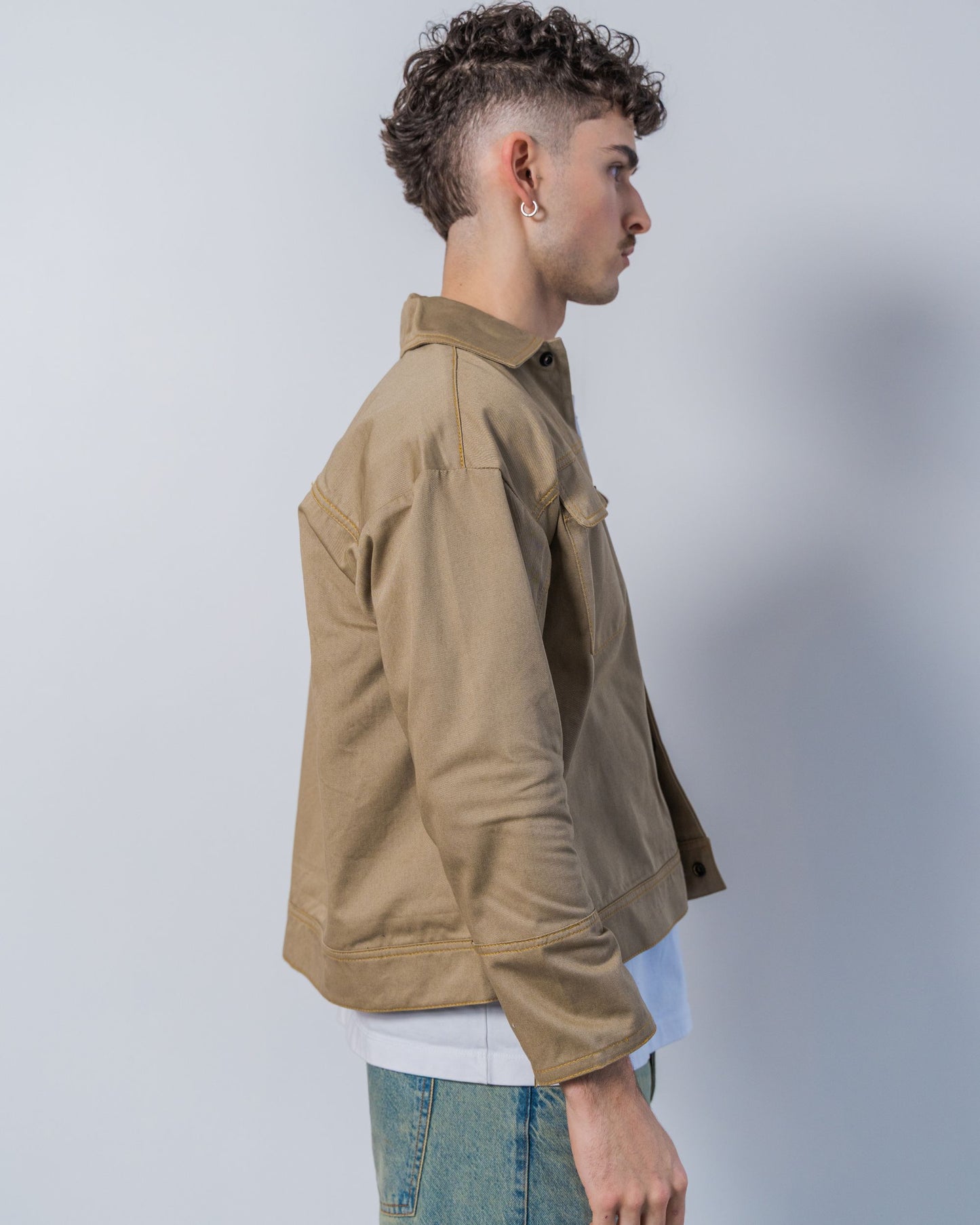 Person wearing a twill weave camel jacket against a white background. The jacket is made from sustainable upcycled materials and unisex.