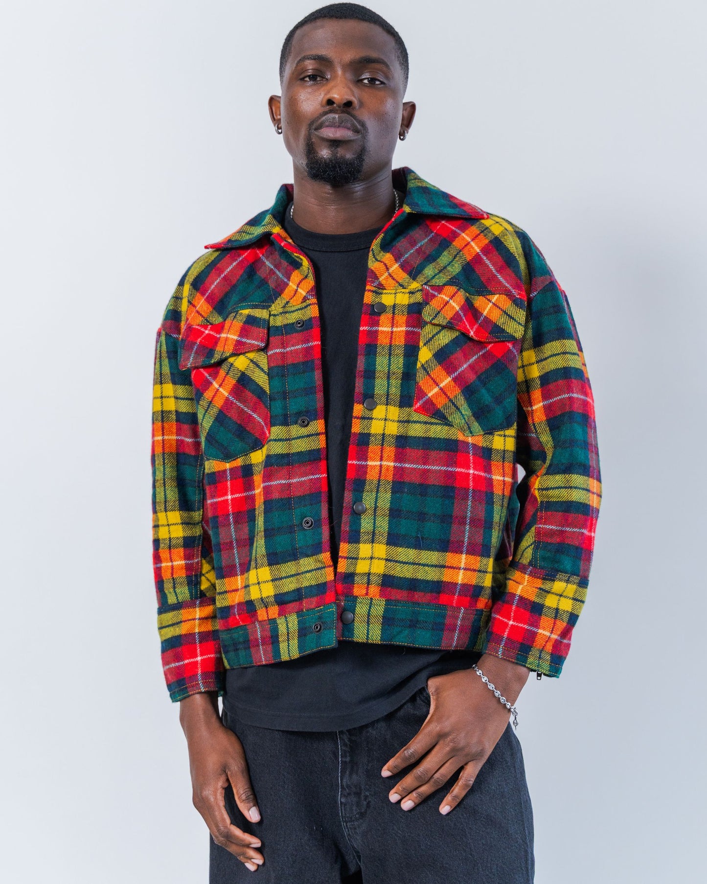 Man wearing a colorful upcycled wool plaid jacket against a white background