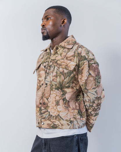 Man wearing a floral patterned jacket on a white background. The jacket is pink and brown with a jacquard floral print. It is sustainable, upcycled and unisex. 