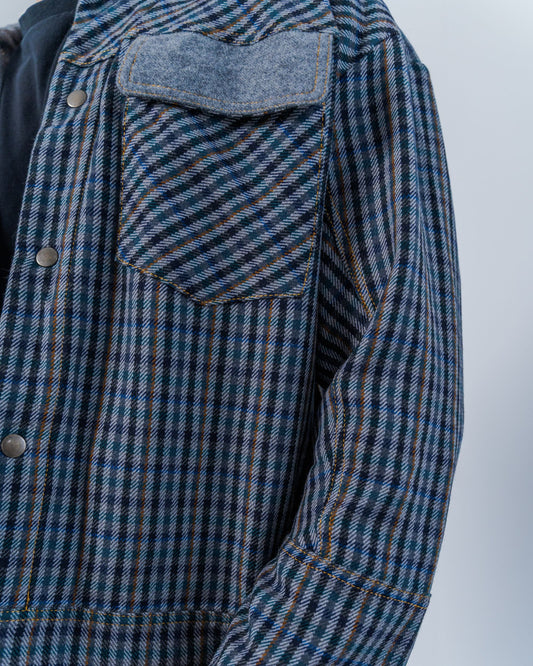 Man wearing a wool plaid jacket The jacket is sustainable and unisex, made from upcycled high quality wool materials. Close up shows the snaps and gold thread top stitching.