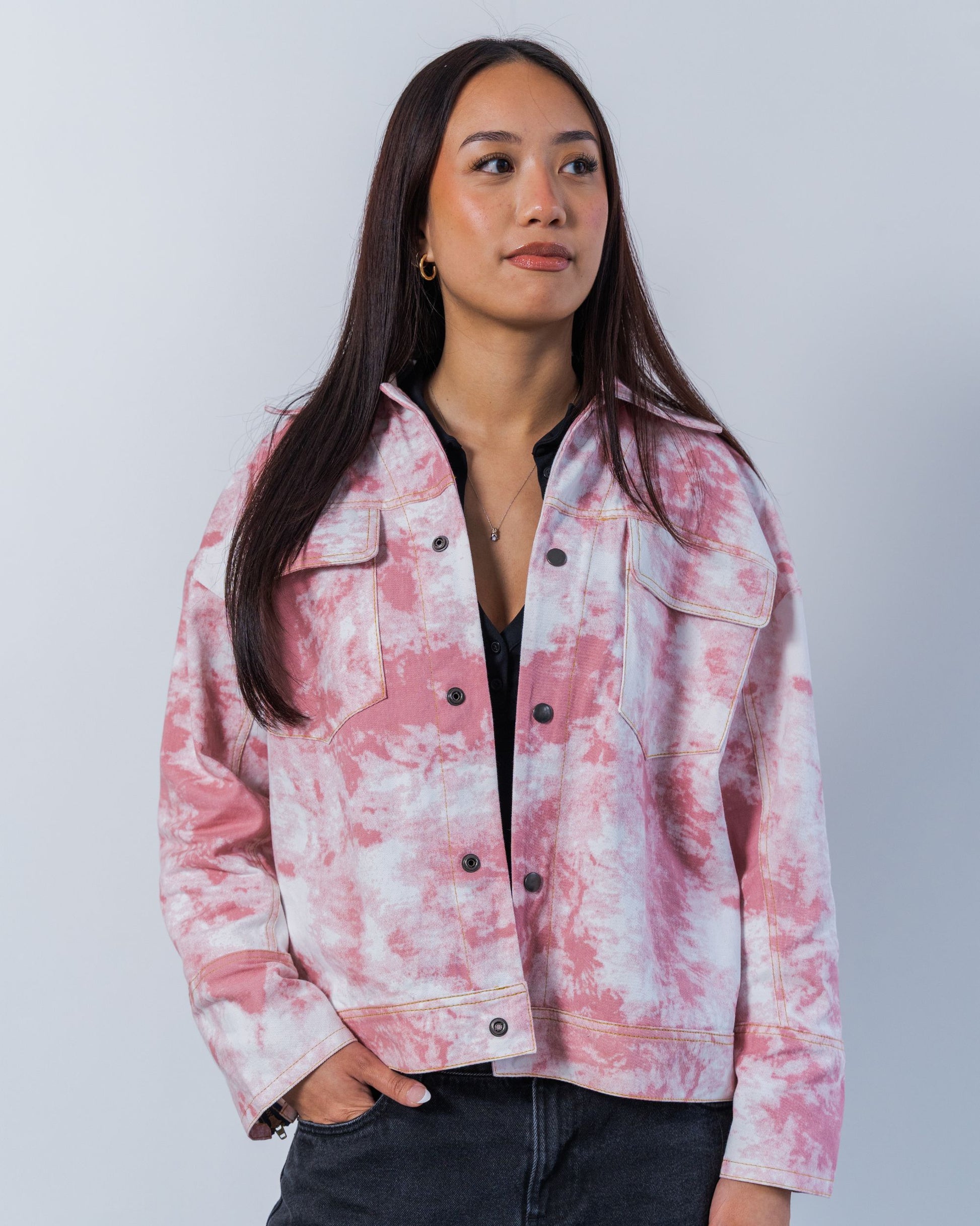 Woman wearing a pink and white tie-dye jacket against a plain background