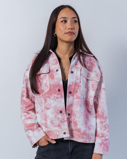 Woman wearing a pink and white tie-dye jacket against a plain background