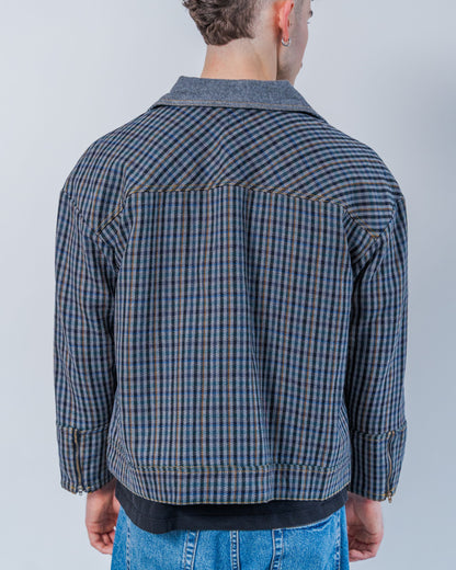 Man wearing a wool plaid jacket The jacket is sustainable and unisex, made from upcycled high quality wool materials. This photo shows the back of the jacket. 