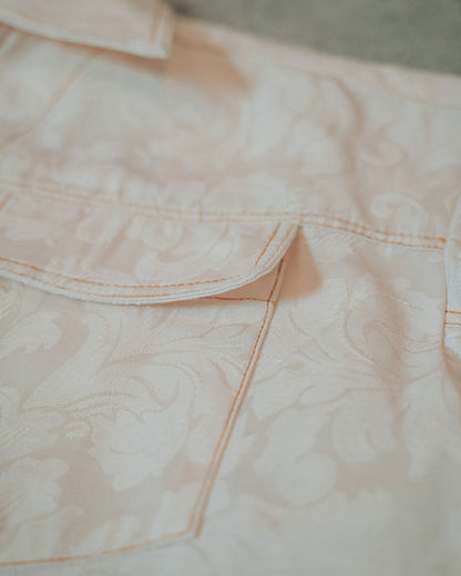 Close-up of a cream jacket pocket with top stitching on a blurred background