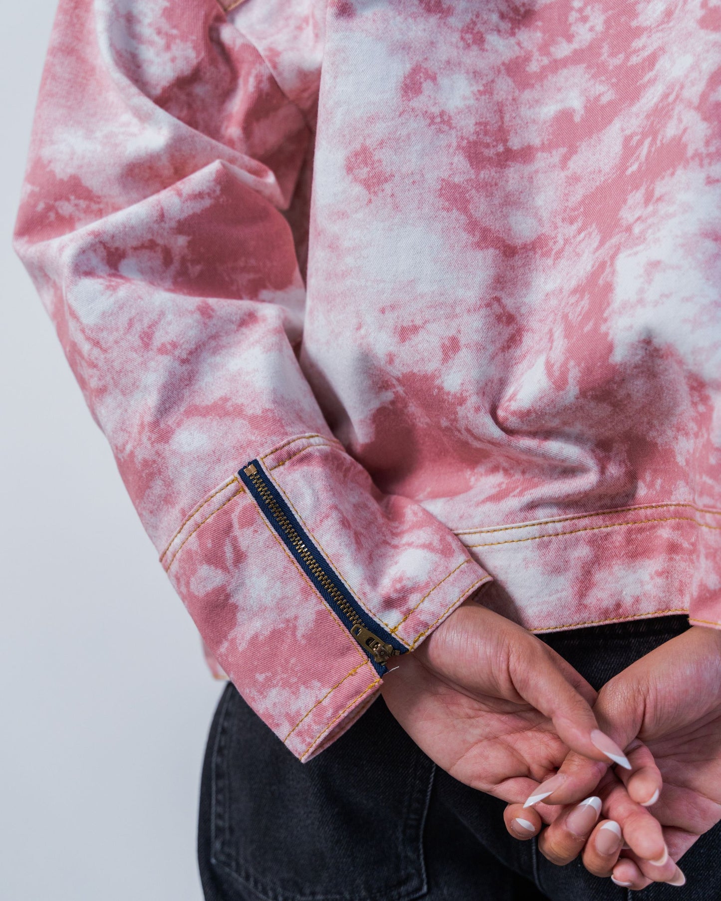 Close-up of zipper details on a pink tie-dye jacket with made from sustainable upcycled materials on a white background
