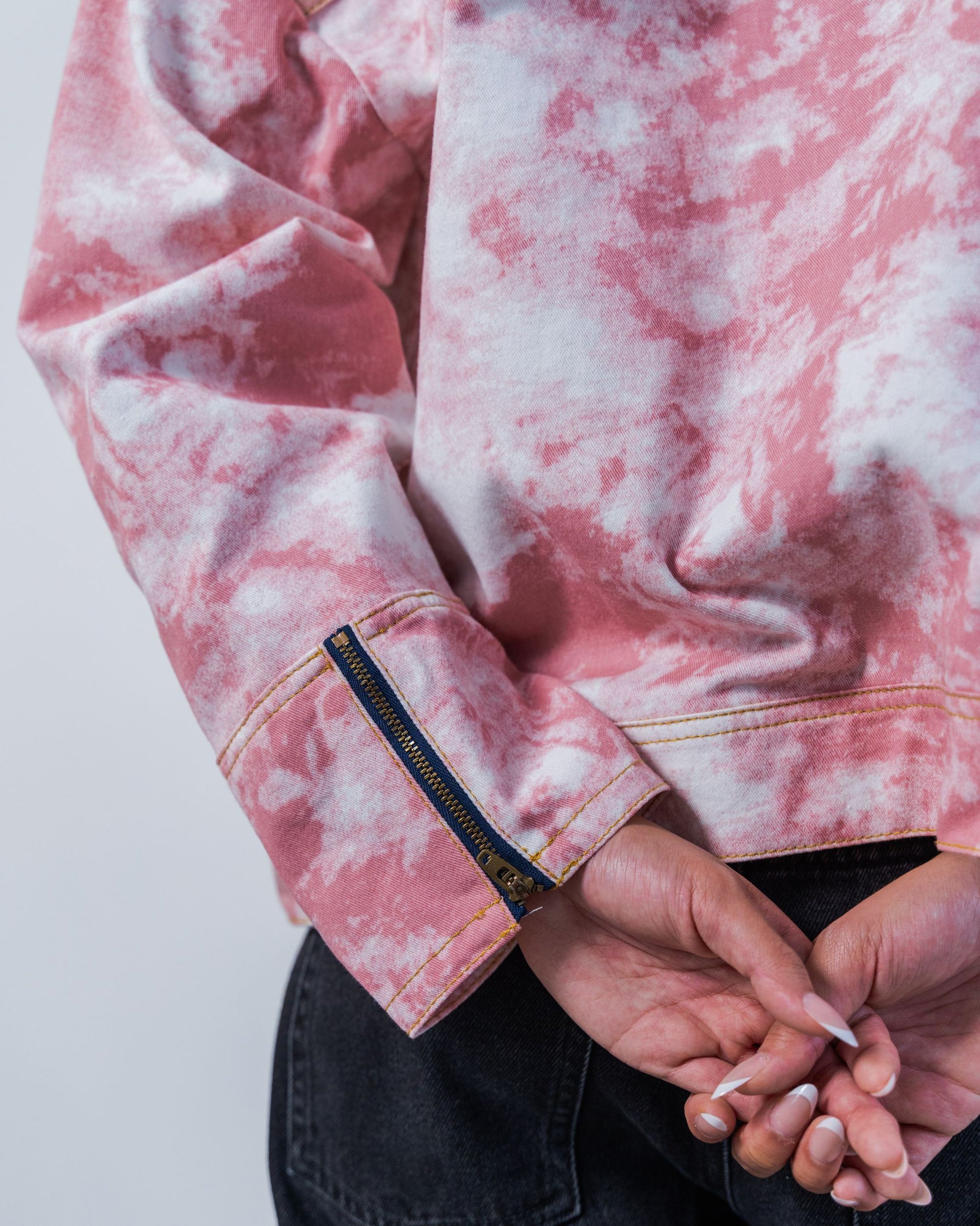 Close-up of zipper details on a pink tie-dye jacket with made from sustainable upcycled materials on a white background