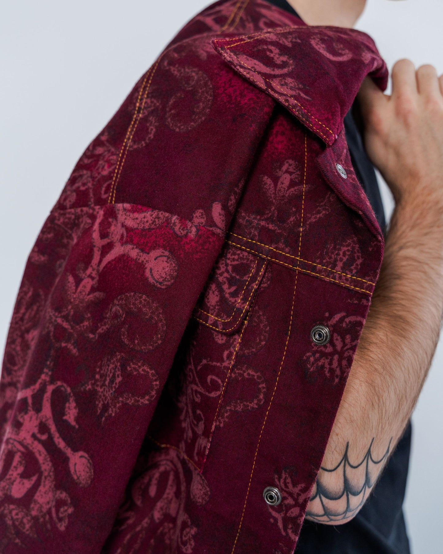 Close-up of burgundy patterned jacket with snaps and gold top stitching