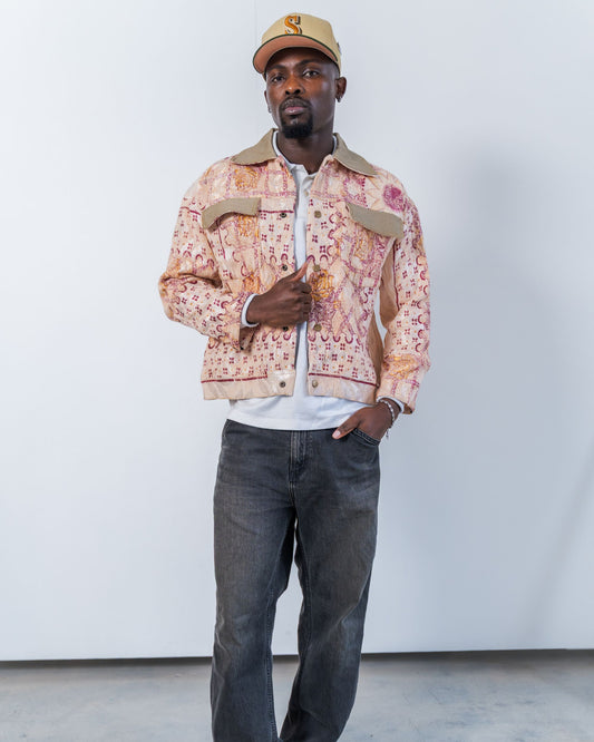 Man wearing a patterned upcycled jacket made from sustainable materials and cap against a white background