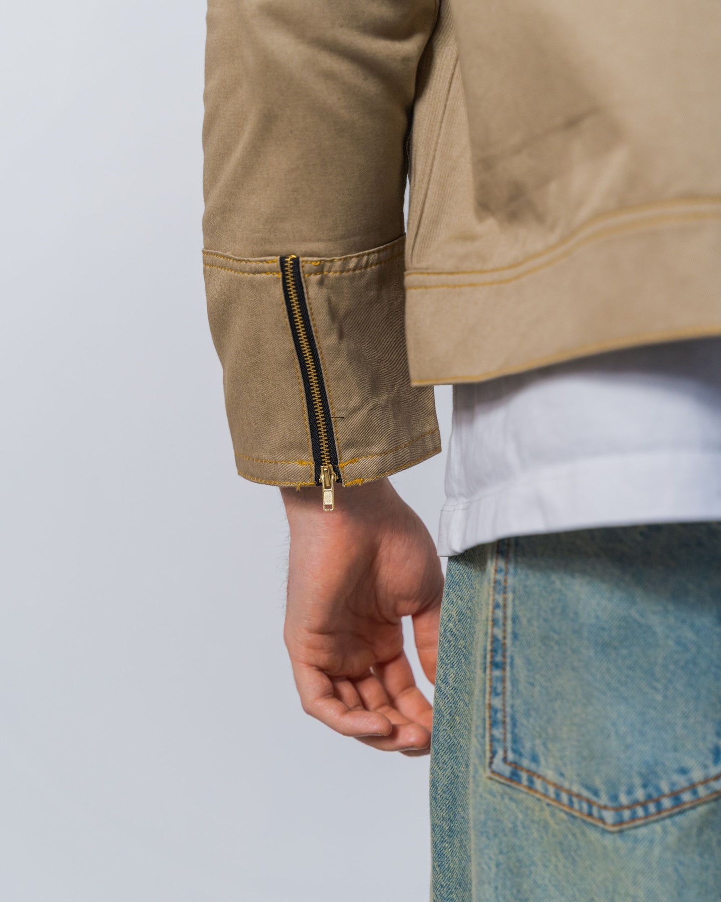Close-up of a twill weave camel jacket with zipper details on the back