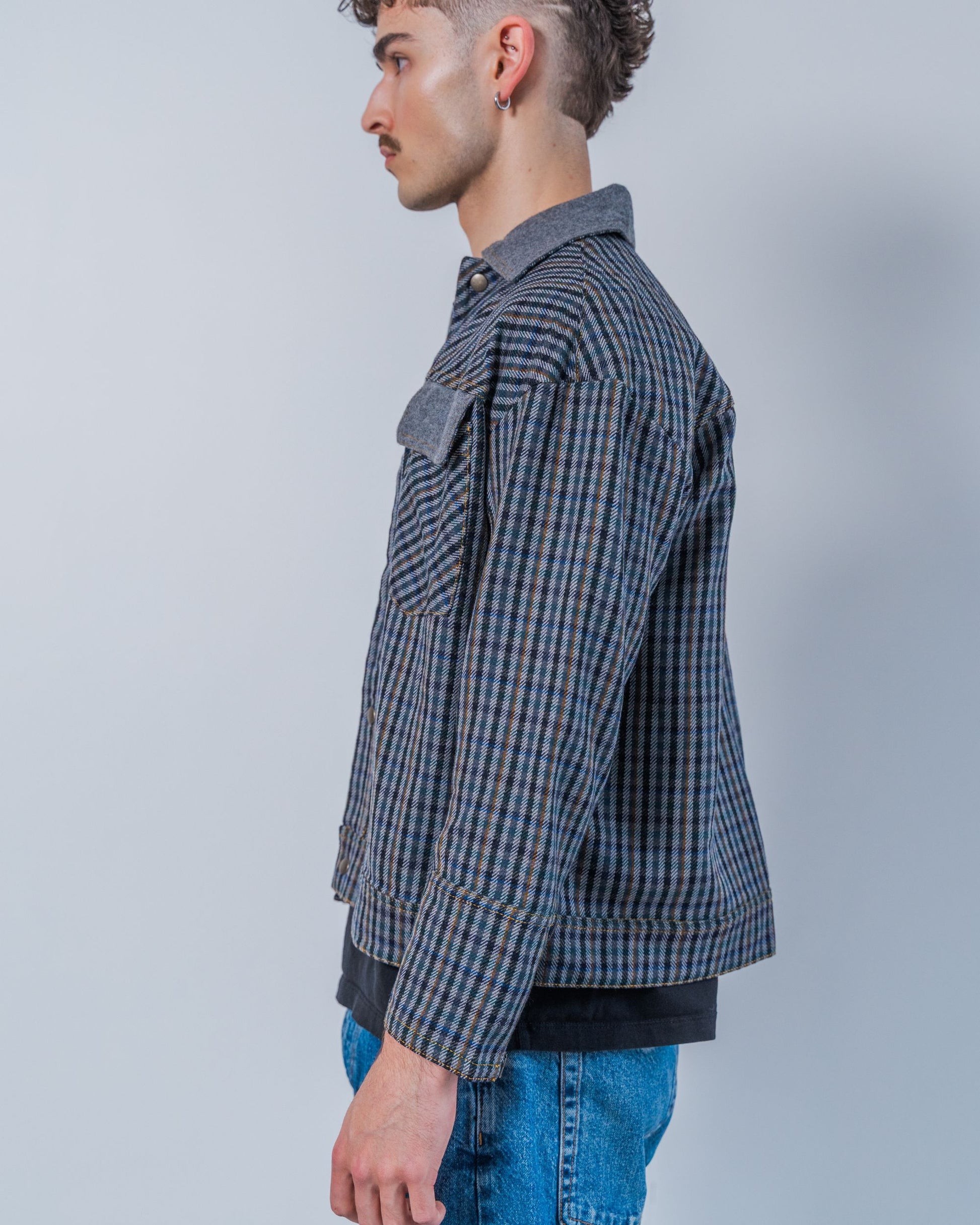 Man wearing a wool plaid jacket The jacket is sustainable and unisex, made from upcycled high quality wool materials. This photo shows the side of the jacket.