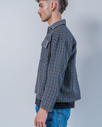 Man wearing a wool plaid jacket The jacket is sustainable and unisex, made from upcycled high quality wool materials. This photo shows the side of the jacket.