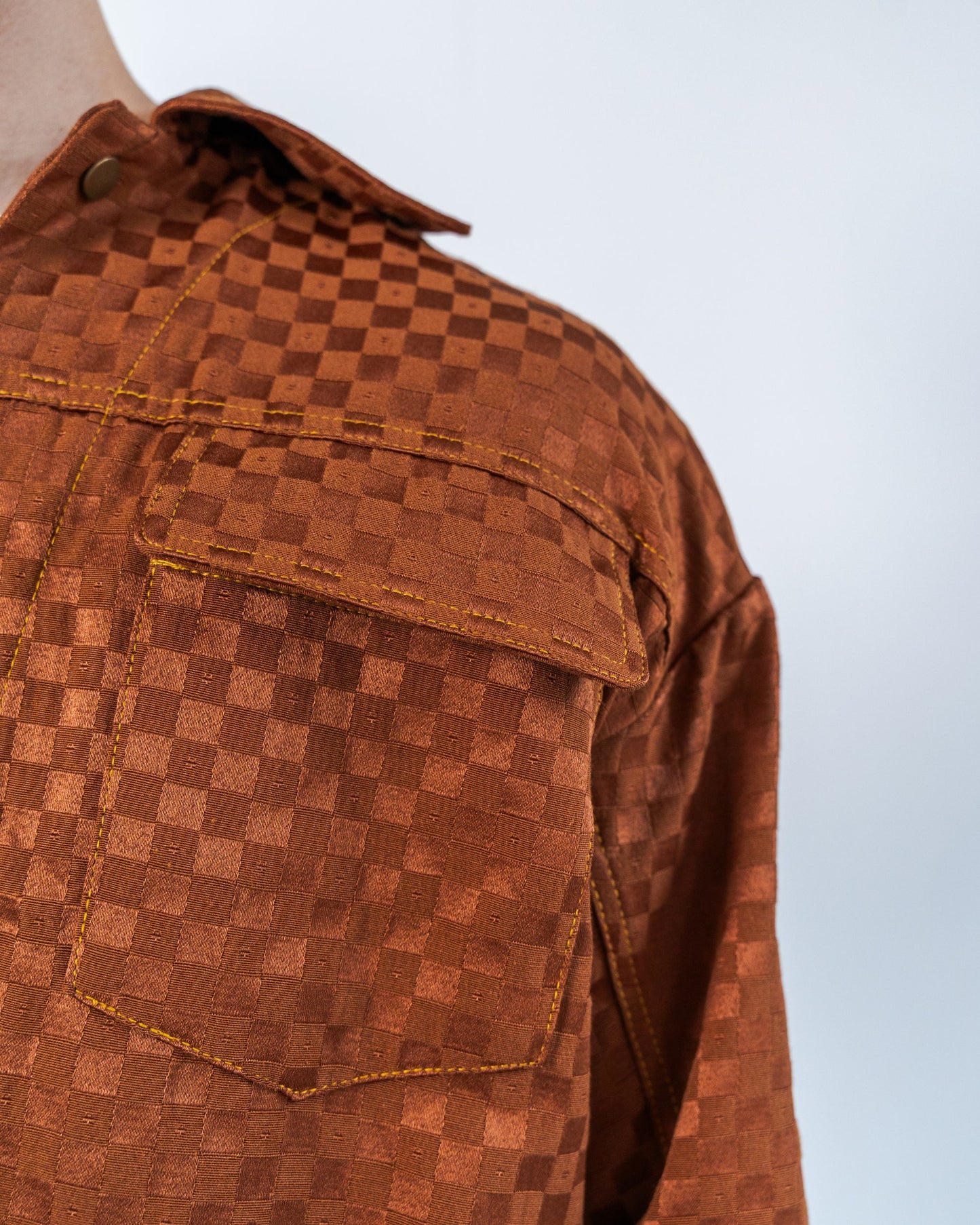 Close up on the sustainable upcycled jacket showing the checkered print and gold topstitching