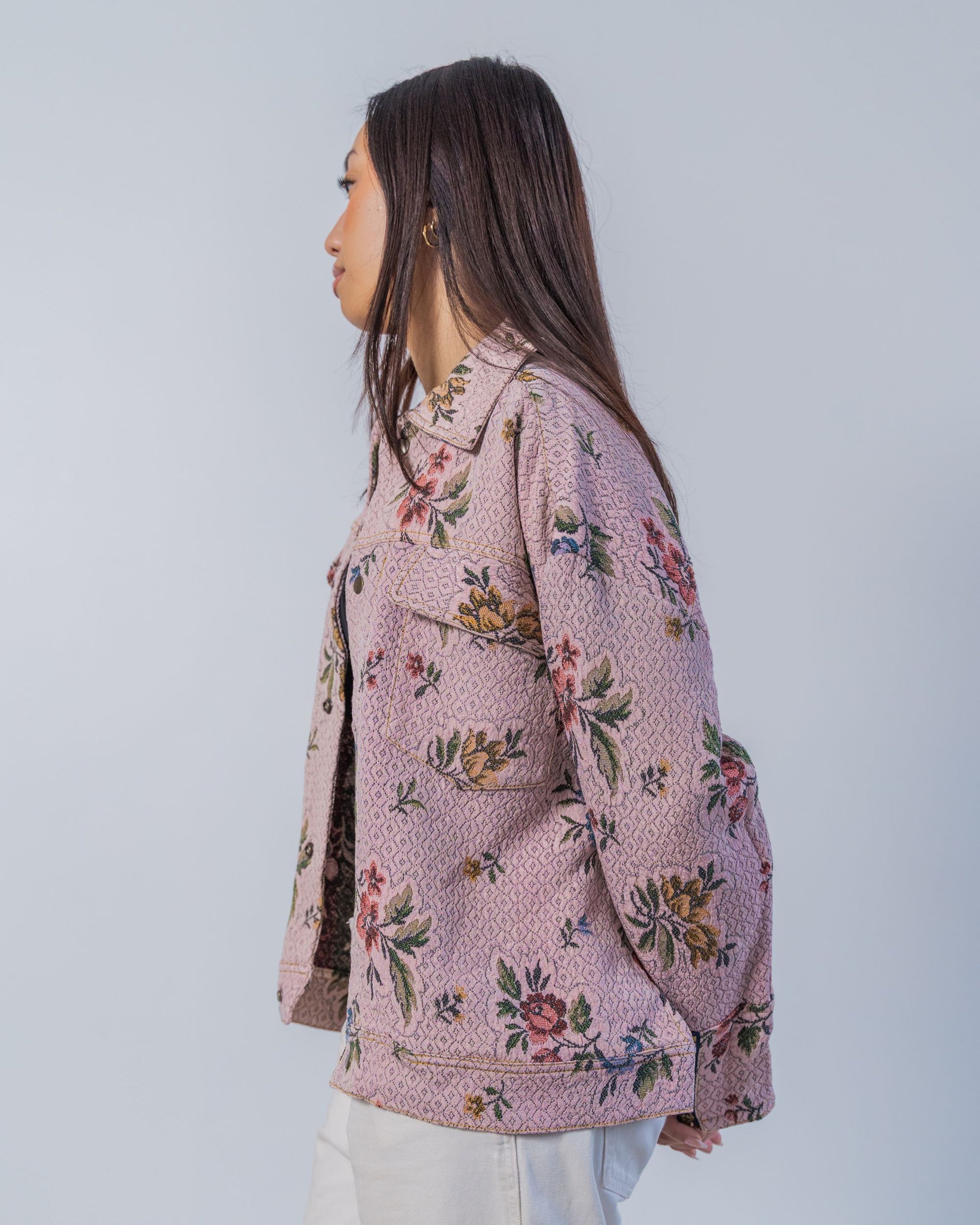 Woman wearing a unisex floral patterned jacket made from sustainable upcycled materials.