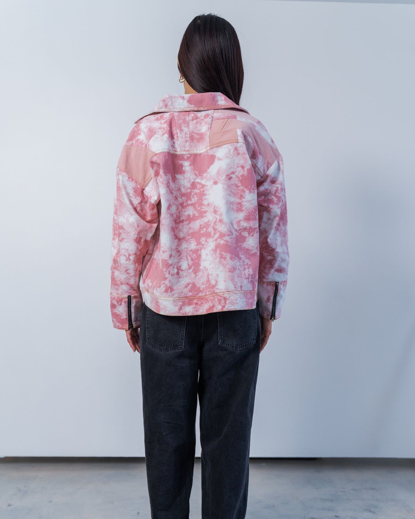 The back of a pink and white tie dye print jacket with patchwork denim in the back panel. Made from upcycled materials