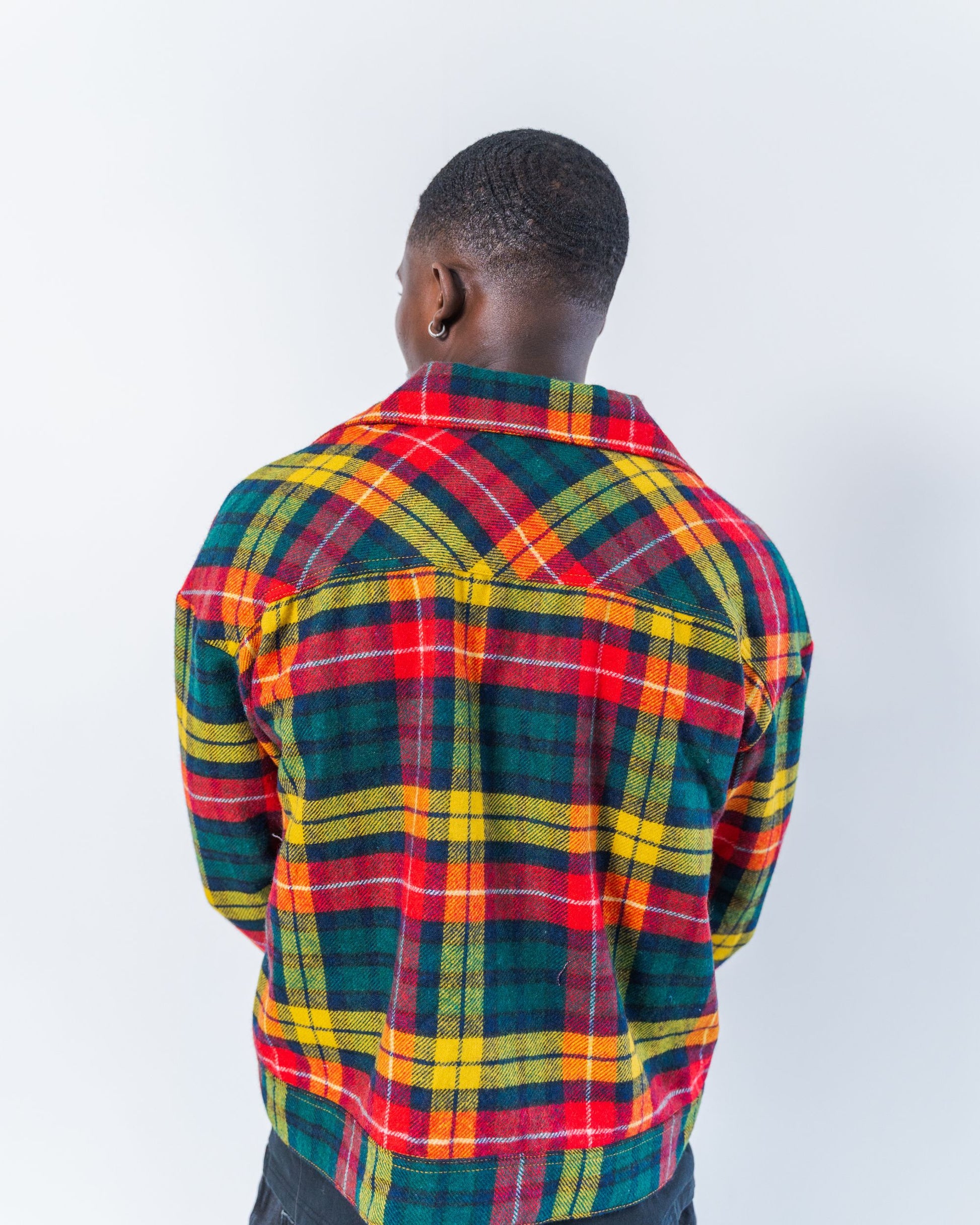 Person wearing a upcycled wool colorful plaid shirt on a white background