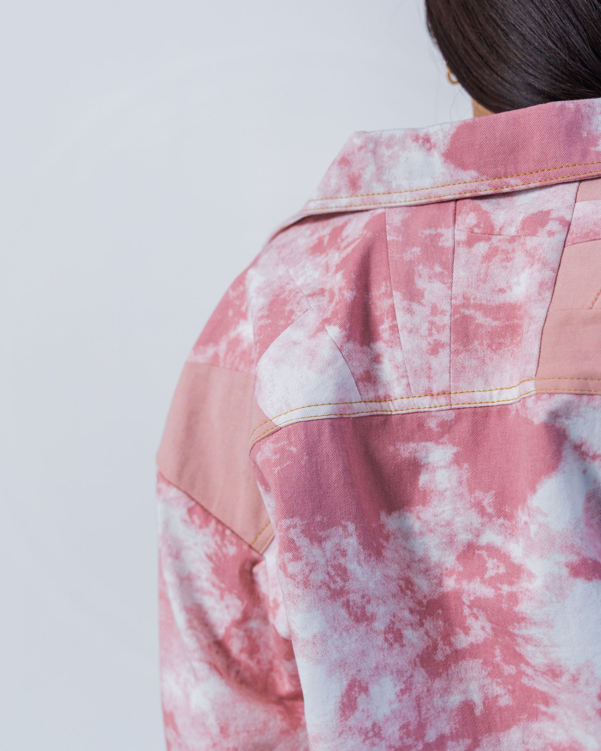 close up of patchwork and topstitching on the back of a jacket made from upcycled materials. 