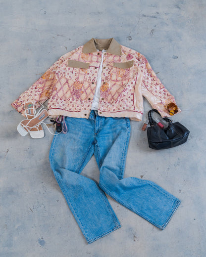 Flat lay styling of the sustainable unisex jacket with jeans, and accessories on a concrete floor. 