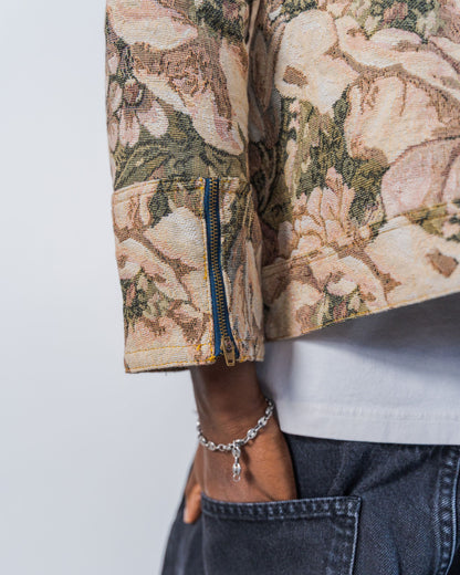 Close-up of a person wearing a floral-patterned jacket with a plain background. This shows the upcycled zipper detail on the cuff. 