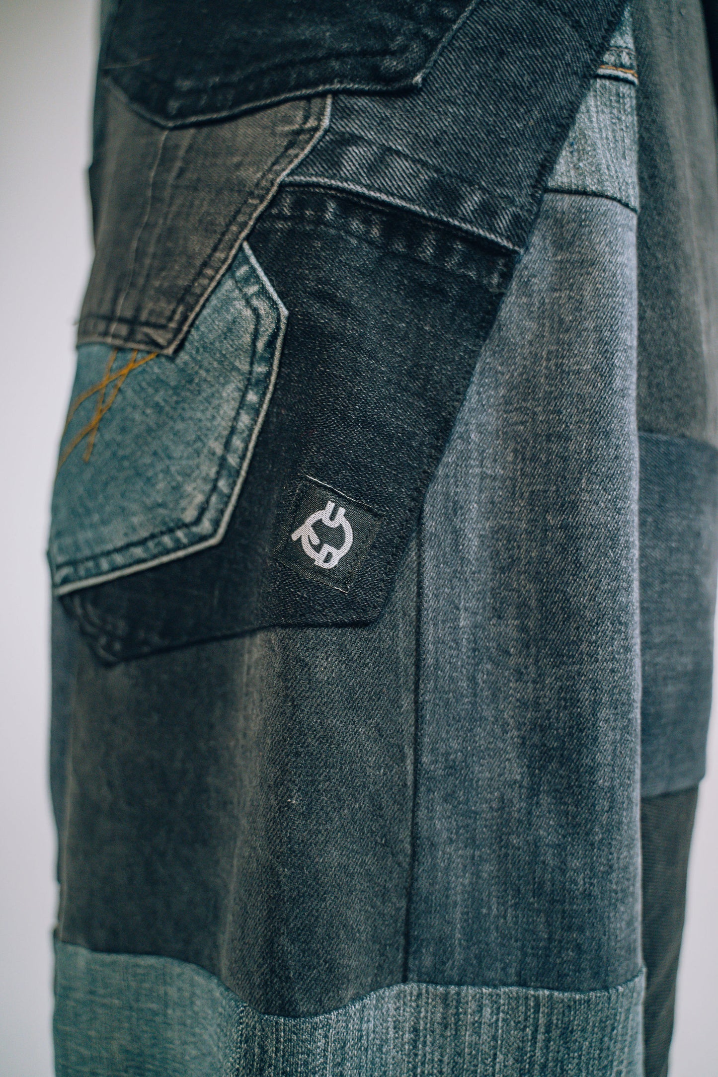 Close-up of a patchwork denim pants with a visible brand logo.