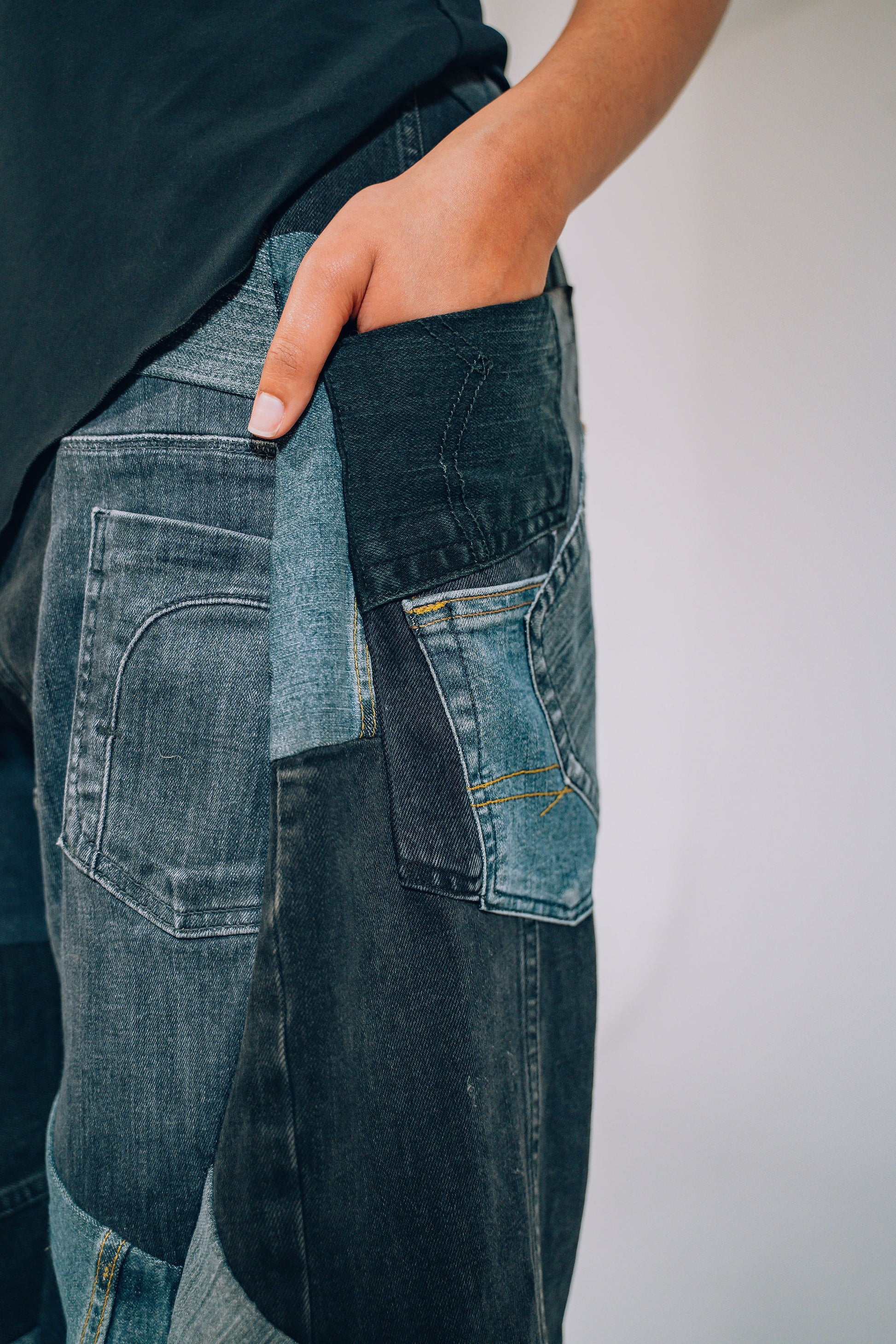 Person wearing patchwork jeans with a plain background