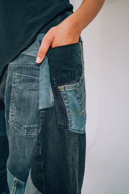 Person wearing patchwork jeans with a plain background
