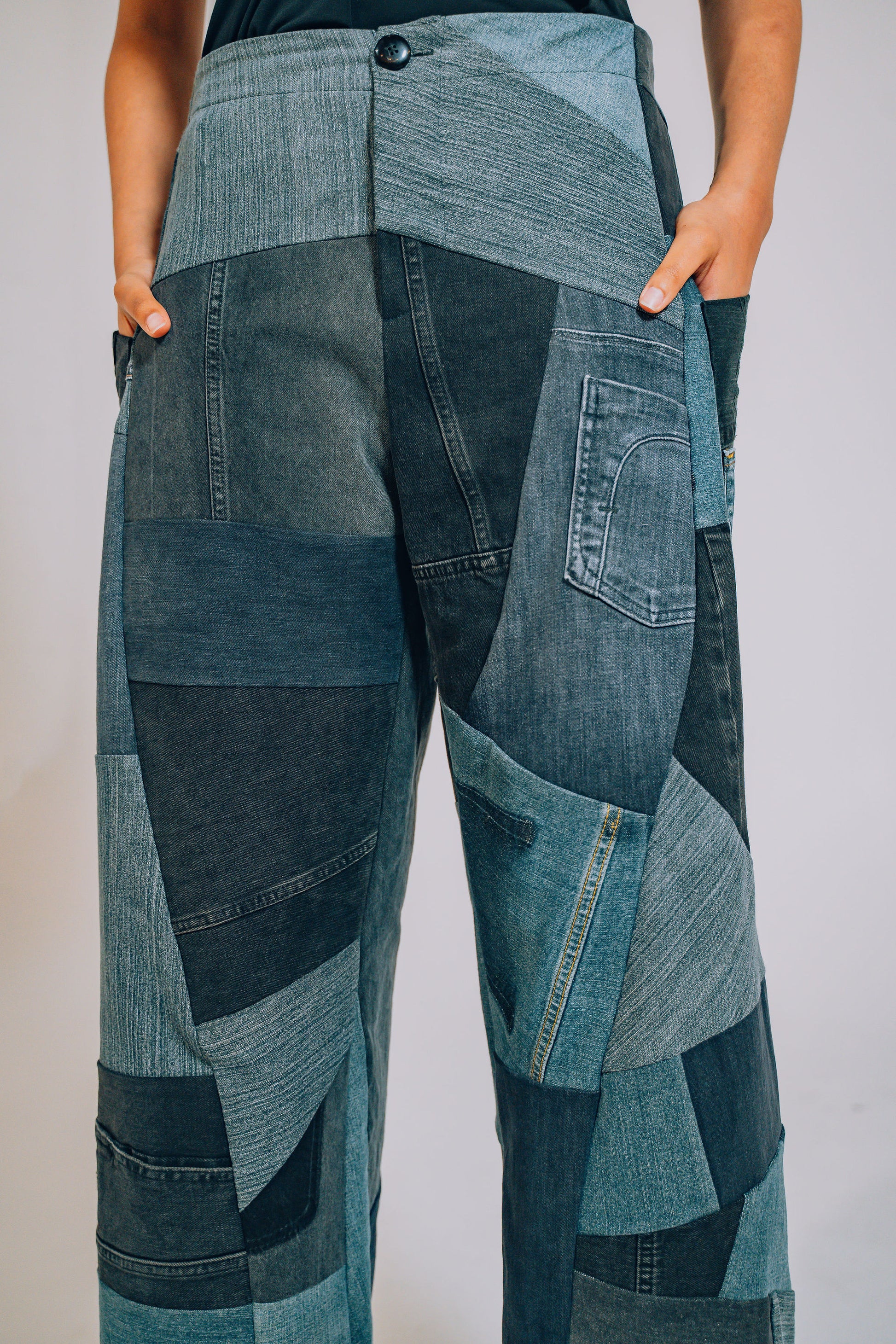 Patchwork jeans worn by a person on a plain background