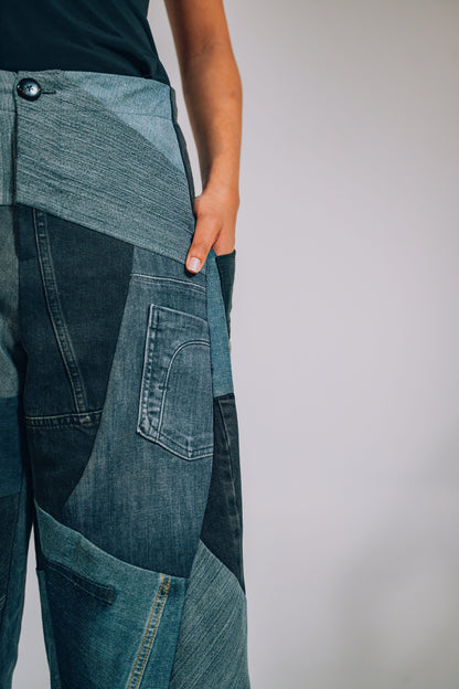 Close-up of a person wearing patchwork jeans against a plain background